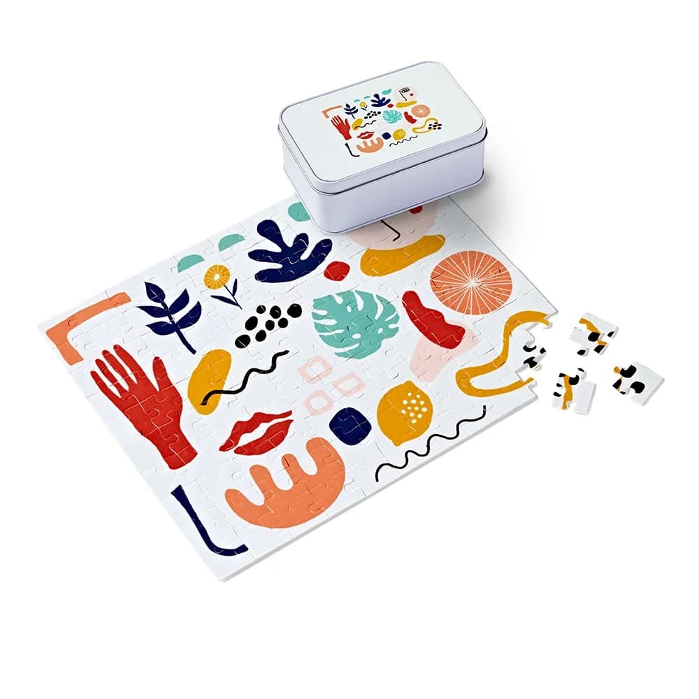 A finished jigsaw beside its printed gift tin
